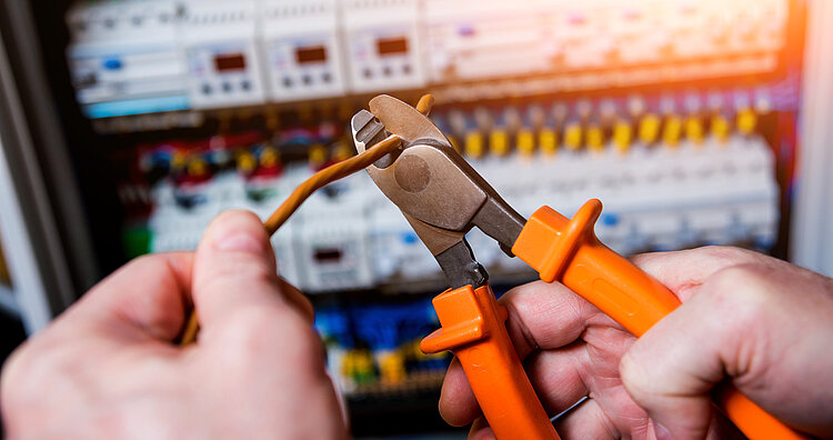 Der Mann repariert die Spannung der Schalttafel mit automatischen Schaltern.